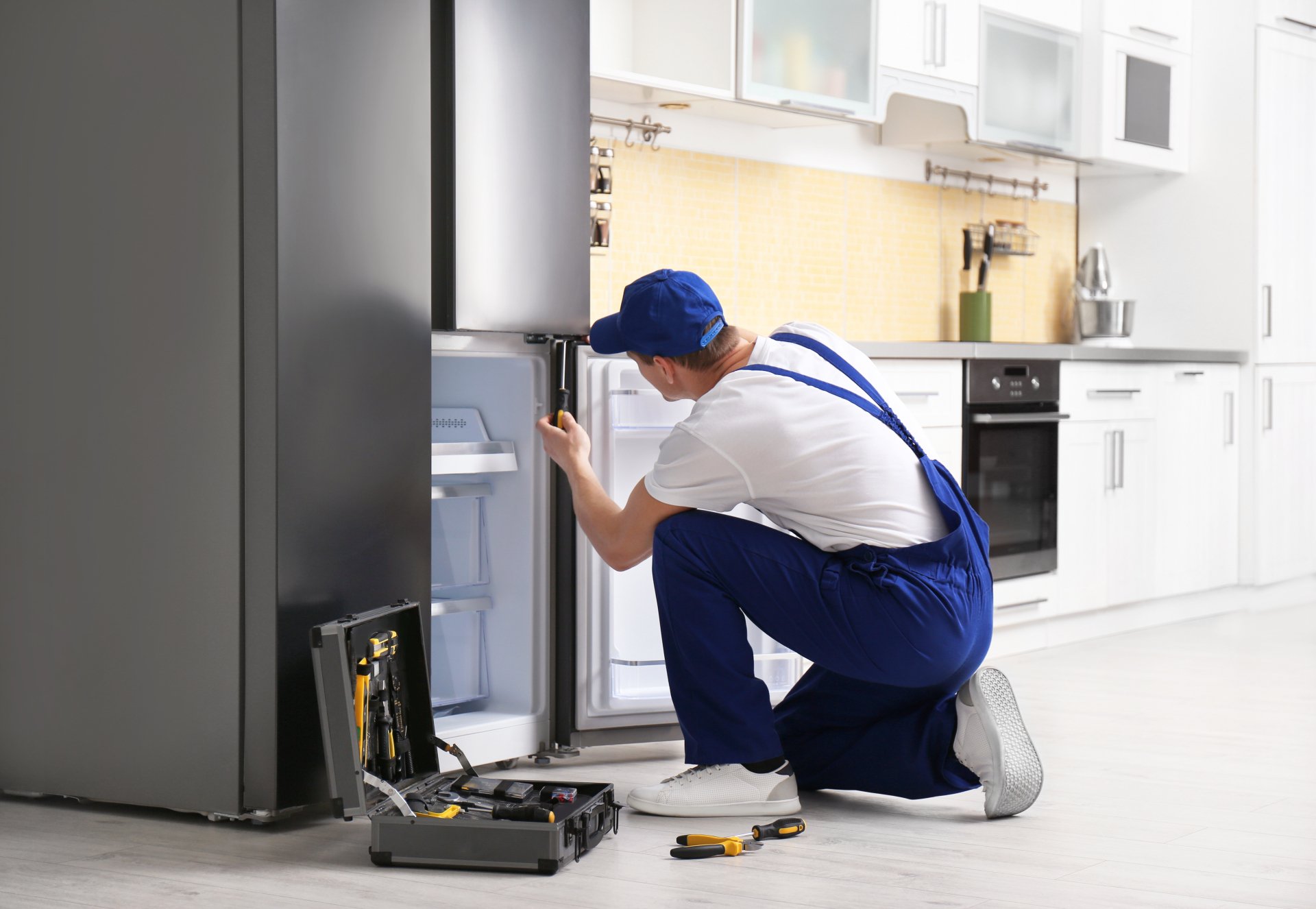 a technician repairing a refrigerator - Athens Appliance Repair Pros
