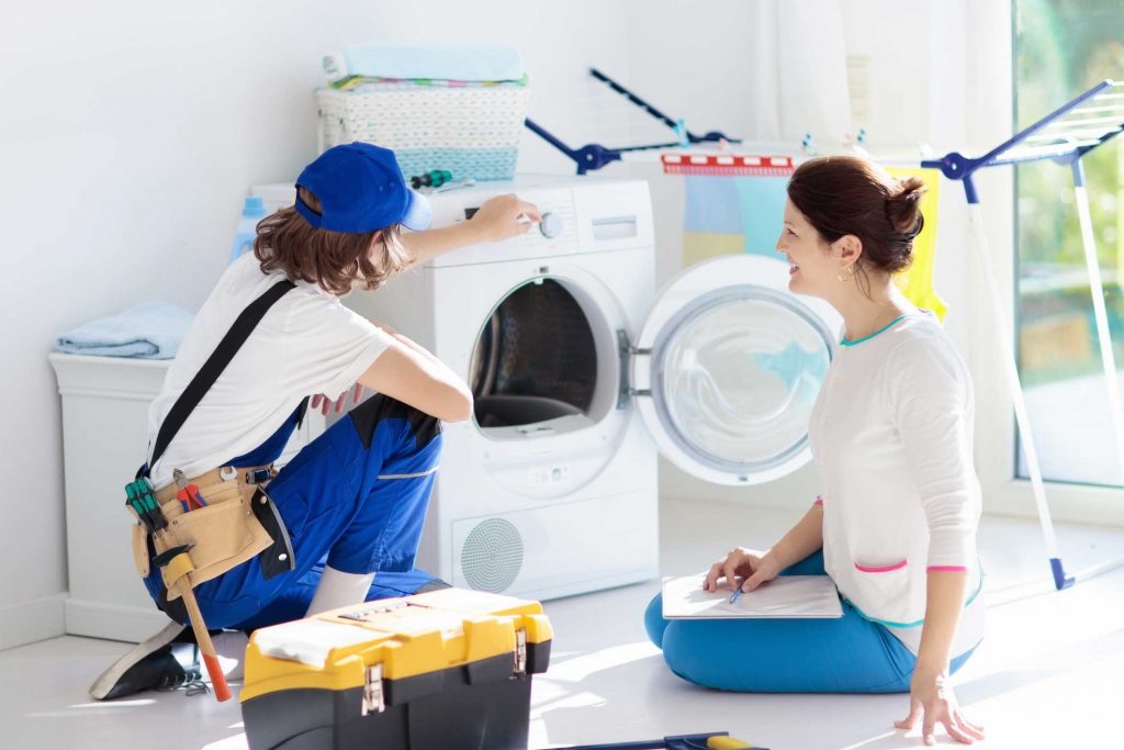 a technician repairing a washer while woman is watching - appliance repair service Athens
